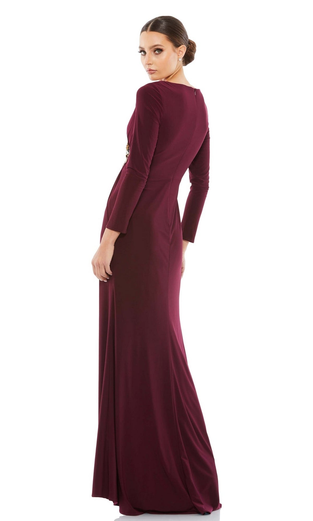 A woman in the Mac Duggal 67848 long sleeve long formal dress stands with her back to the camera, glancing over her shoulder against a plain white background.